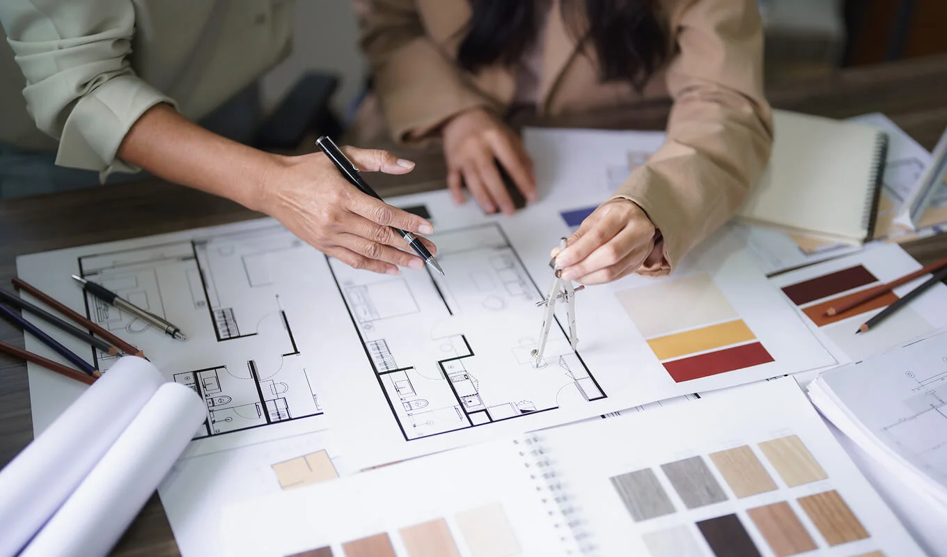 two female architects discuss building project and use divider compass